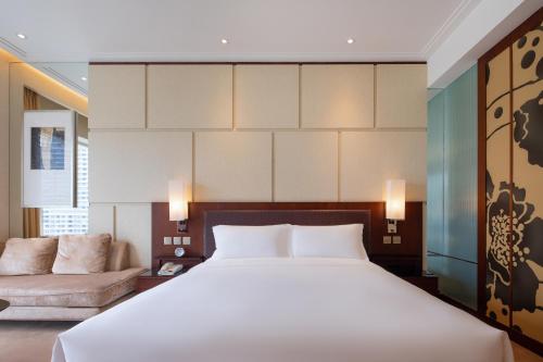 a bedroom with a large bed and a couch at New World Dalian Hotel in Dalian