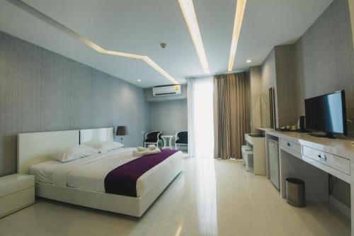 a bedroom with a bed and a television and a desk at Phuglong Hotel in Phayao
