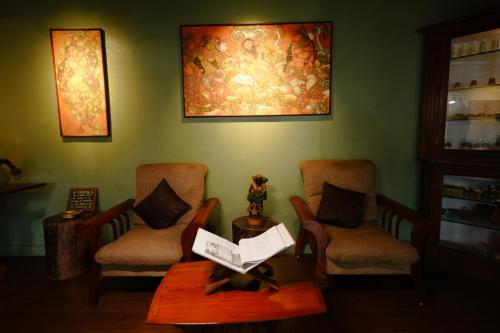 a room with two chairs and a table and a painting at Blackberry Hills Munnar Nature Resort & Spa in Munnar