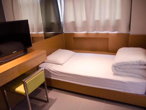 a small bedroom with two beds and a television at Acesite Knutsford Hotel in Hong Kong