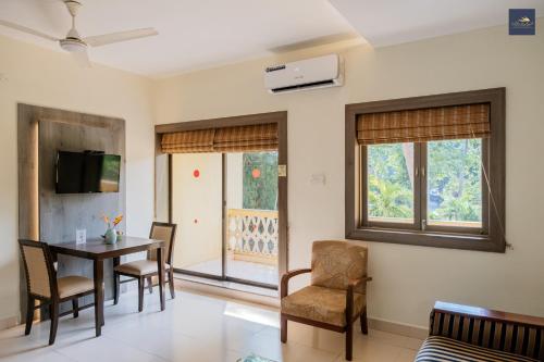 a living room with a table and chairs and windows at Golden Landmark Green Valley Beach Resort in Dona Paula
