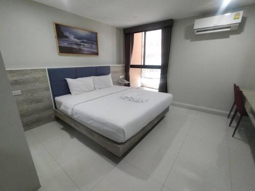 a bedroom with a large white bed with a blue headboard at Sattahip 9 Boutique Hotel in Pattaya Central