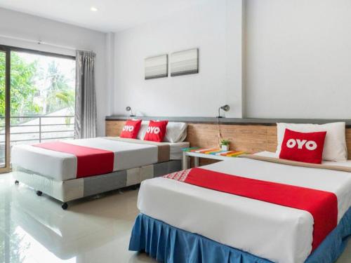 two beds in a room with red and white at OYO 567 U Residence in Ban Lamai