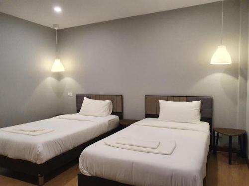 a room with two beds with white sheets and lights at THE S VILLAS HOTEL in Nakhon Phanom