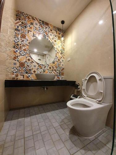 a bathroom with a toilet with a mirror and a sink at THE S VILLAS HOTEL in Nakhon Phanom