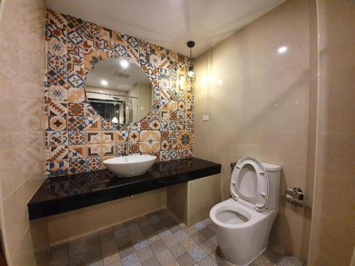 a bathroom with a toilet and a sink and a mirror at THE S VILLAS HOTEL in Nakhon Phanom