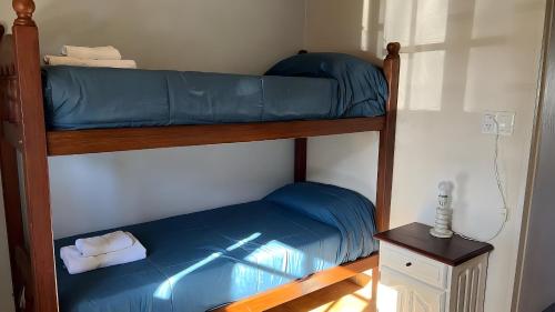 a bedroom with two bunk beds with blue sheets at Complejo de Bungalows del Lago Km13 in San Carlos de Bariloche