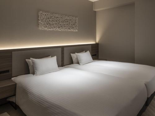 a large bed with white pillows in a room at HOTEL FORZA SAPPORO STATION in Sapporo