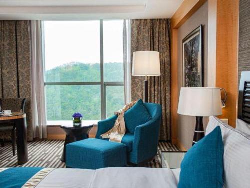 a hotel room with a bed and chairs and a window at Grand Mercure Teda Dalian in Dalian