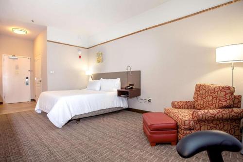 a hotel room with a bed and a chair at Hilton Garden Inn Oshkosh in Oshkosh