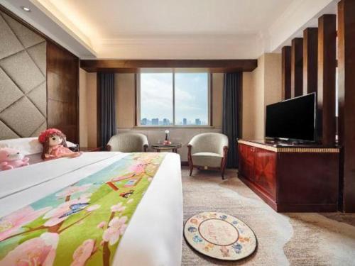 a hotel room with a bed and a flat screen tv at New Century Hotel Taizhou 