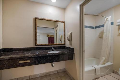 a bathroom with a sink and a tub and a mirror at Americas Best Value Inn Redlands San Bernardino in Redlands