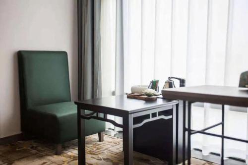 a green chair and a table in a room at New Friendship Hotel in Luoyang