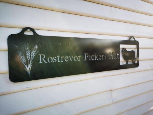 a sign for a rooster picks hut hanging on a wall at Rostrevor Pickers Cottage in Triabunna