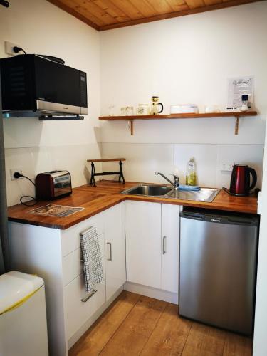 a small kitchen with a sink and a microwave at Rostrevor Pickers Cottage in Triabunna