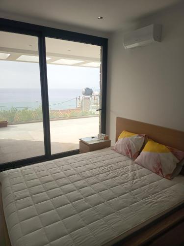 ein Schlafzimmer mit einem großen Bett und einem großen Fenster in der Unterkunft Plomari View Stone Apartments in Plomari