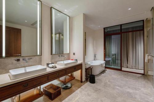 a bathroom with two sinks and a tub and a toilet at Pingtian Bandao Hotel in Chizhou