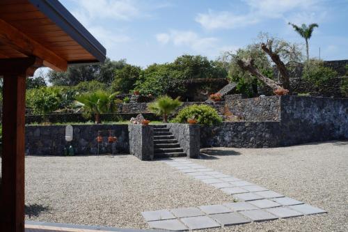 a garden with a stone wall and a stone path at Profumo di Zagara Acireale in Acireale