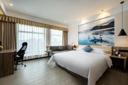 a hotel room with a large white bed and a desk at hailihotel in Dongguan