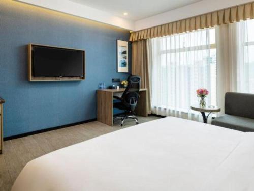 a hotel room with a bed and a desk and a television at hailihotel in Dongguan