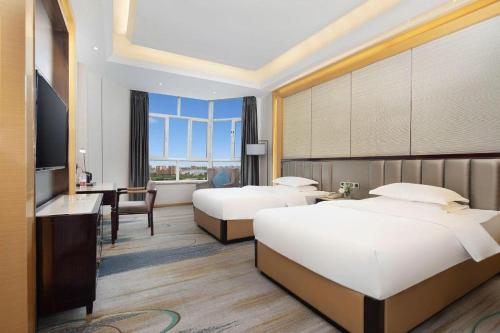 a hotel room with two beds and a desk at Metropolo Hotel Yining Development Zone Hanma Building in Kipekyüzi