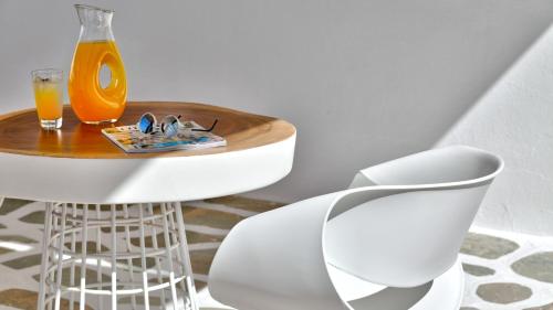 a table with a glass of orange juice and a white chair at Lilly Residence-All Sea View Suites, Adults Only in Naousa