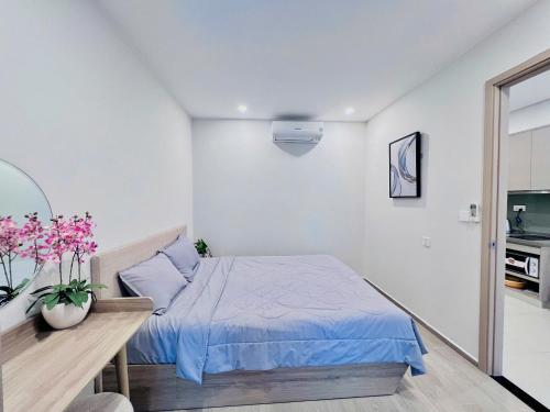 a bedroom with a bed and a table with flowers at PƠ Homestay THESONG Vũng Tàu in Vung Tau