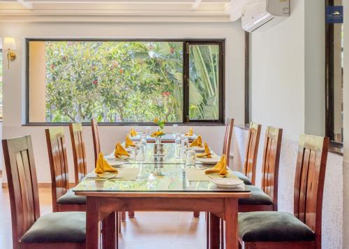 a dining room with a long table and chairs at Golden Landmark Green Valley Beach Resort in Dona Paula