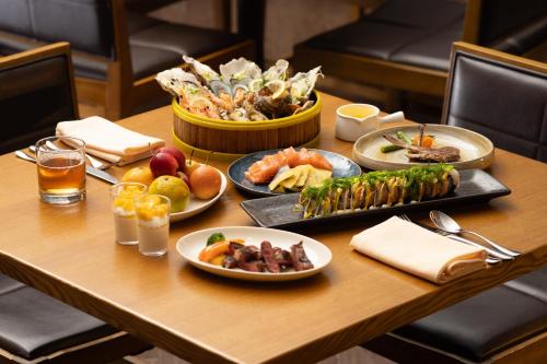 a wooden table with plates of food on it at New World Dalian Hotel in Dalian