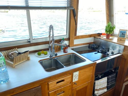 une cuisine avec un évier et deux fenêtres dans l'établissement Nuit insolite a bord d un bateau, à Caen