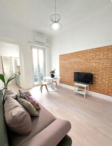 a living room with a couch and a brick wall at Petite Deva - Central loft with balcony in Cagliari