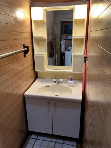 a bathroom with a sink and a mirror at KeNJIRO HOUSE in Oshirabetsu