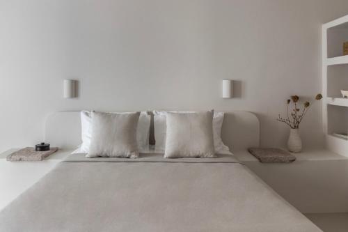 a white bedroom with a large bed with pillows at Om Living Milos in Pollonia