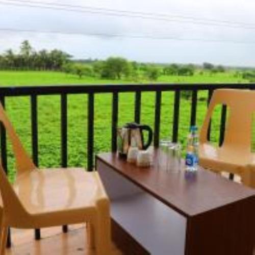 a table and chairs on a balcony with a view of a field at VITS Select Diamond Resort Sasan Gir in Talala