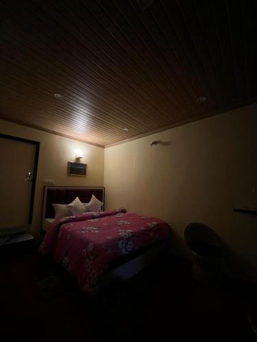 a bedroom with a bed with a red comforter at Gangamaya Homestay in Darjeeling