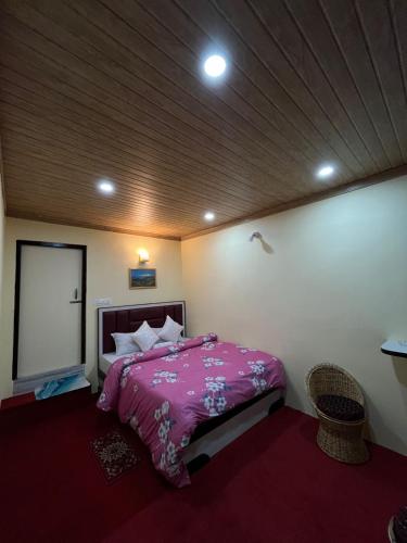 a bedroom with a pink bed and a wooden ceiling at Gangamaya Homestay in Darjeeling