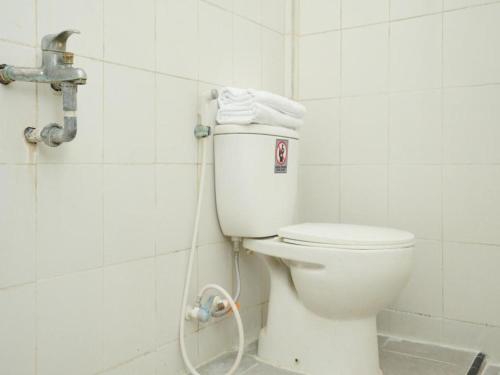 a white toilet in a bathroom with a hose at OYO 2003 Female Guest House in Probolinggo