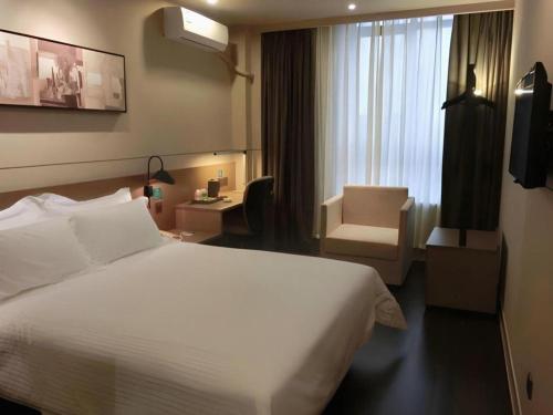 a hotel room with a white bed and a chair at Jinjiang Inn Select Shanghai Fengxian Baolong Square North Yunhe Road in Shanghai