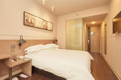 a bedroom with a large white bed and a table at Jinjiang Inn Select Shanghai Fengxian Baolong Square North Yunhe Road in Shanghai