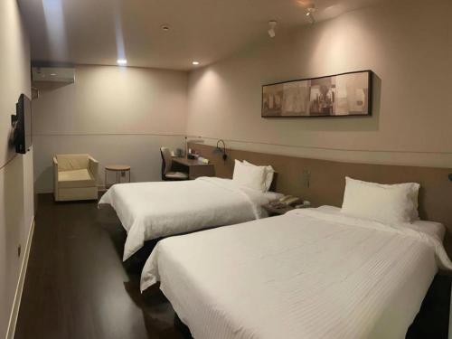a hotel room with two beds and a table with a chair at Jinjiang Inn Select Shanghai Fengxian Baolong Square North Yunhe Road in Shanghai