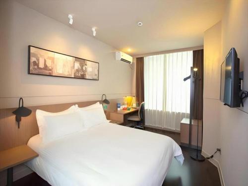 a hotel room with a white bed and a window at Jinjiang Inn Select Shanghai Fengxian Baolong Square North Yunhe Road in Shanghai
