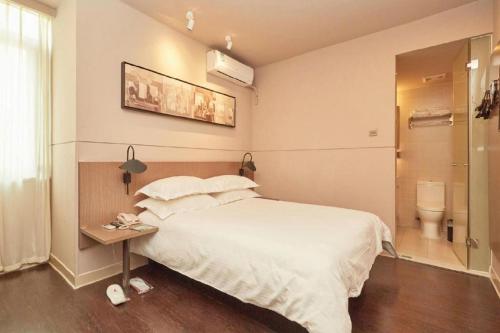 a bedroom with a bed and a bathroom with a toilet at Jinjiang Inn Select Shanghai Fengxian Baolong Square North Yunhe Road in Shanghai