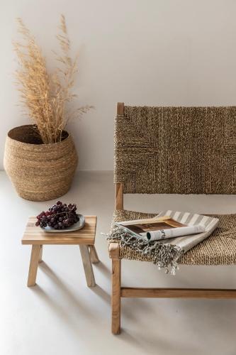 a rattan chair next to a table and a plant at Om Living Milos in Pollonia