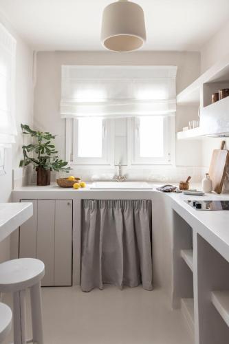 a white kitchen with a sink and a counter at Om Living Milos in Pollonia