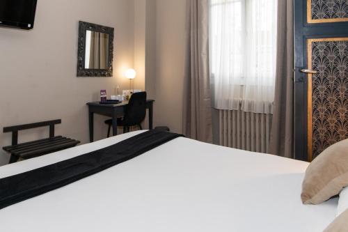 a bedroom with a bed and a desk and a door at The Originals Boutique, Hôtel Victoria, Châtelaillon-Plage in Châtelaillon-Plage