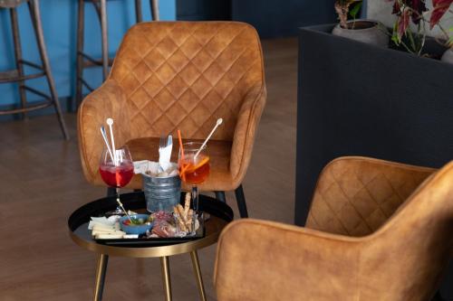 two chairs and a table with two glasses of wine at The Originals Boutique, Hôtel Victoria, Châtelaillon-Plage in Châtelaillon-Plage