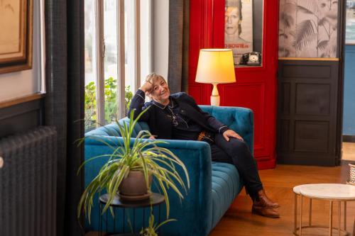 a woman sitting on a couch in a living room at The Originals Boutique, Hôtel Victoria, Châtelaillon-Plage in Châtelaillon-Plage