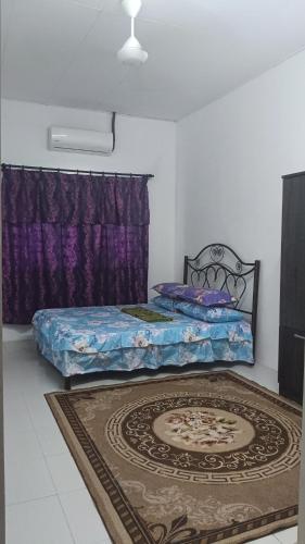a bedroom with a bed and a rug at Ainur Homestay in Kampung Sungai Baharu