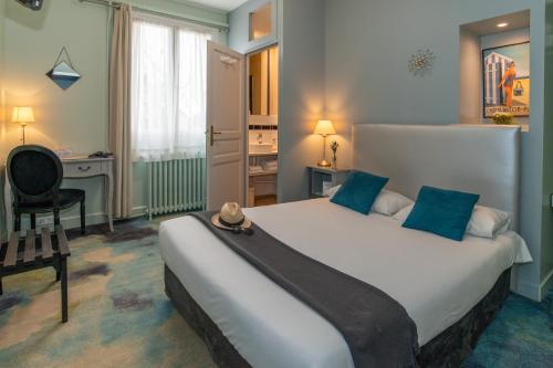 a bedroom with a large white bed with blue pillows at The Originals Boutique, Hôtel Victoria, Châtelaillon-Plage in Châtelaillon-Plage