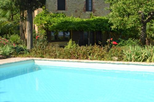 a blue swimming pool in front of a garden at Urlaub, wo die Toskana noch authentisch ist - Rustico aus 16Jh mit Infinity Pool in Pomarance